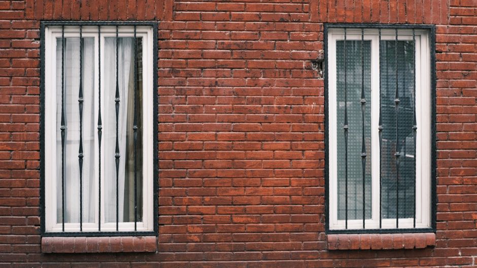 Brick wall of a house with two windows.