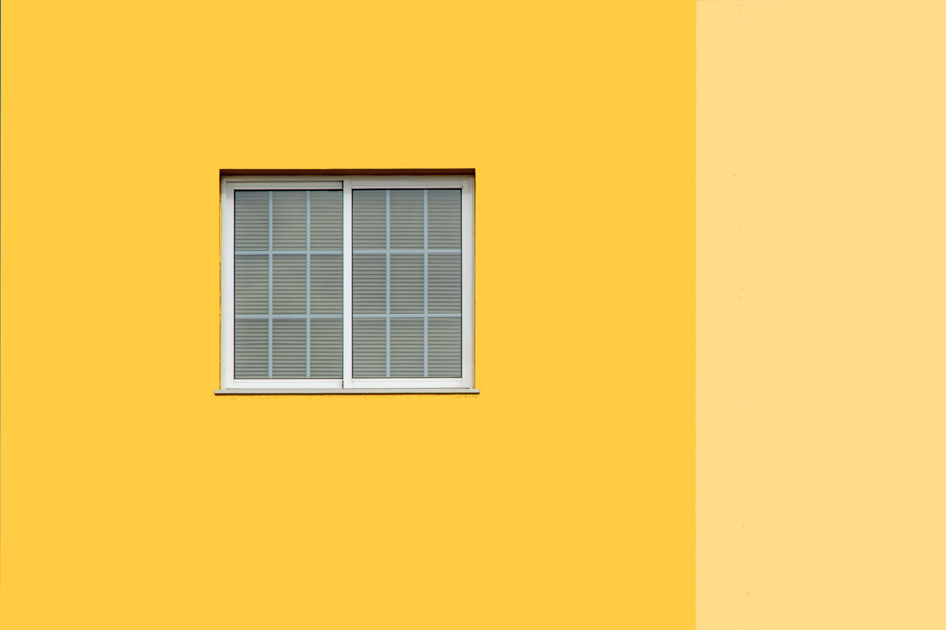 Clean and bright facade with a central white window on a vibrant yellow wall in Riverside, CA